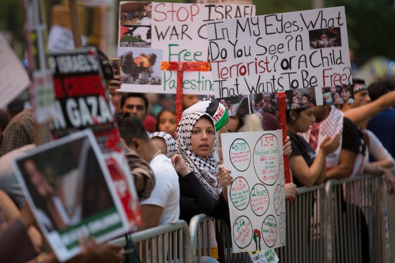A demonstrator is surrounded by signs on Sixth Avenue outside News Corporation during a protest against Israeli military operations in the Gaza Strip, Friday, Aug. 1, 2014, in New York.