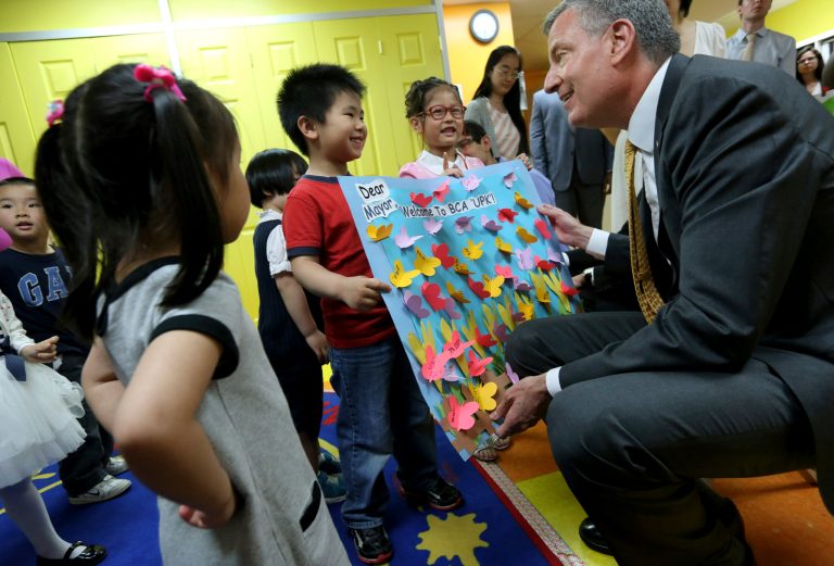 Students present New York Mayor Bill de Blasio, right, with a home-made welcome sign during the mayor's visit to their pre-kindergarten class at the Brooklyn Chinese American Association Early Childhood Education Center in Sunset Park, Brooklyn, Tuesday, May 27, 201. (AP Photo/Newsday, Linda Rosier, Pool)