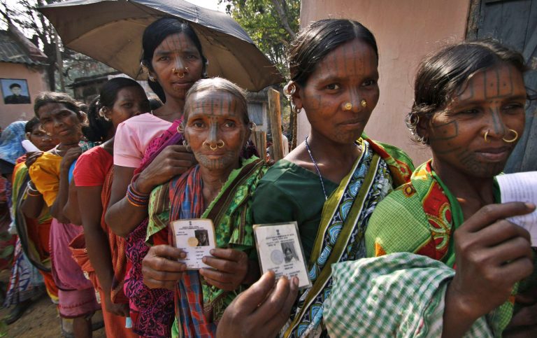 Indigenous women belonging to the Kandha tribe display their voter's identity cards as they wait to cast their votes outside a polling station during Indian parliamentary elections at Dingesiguda village in Kandhamal district, Orissa state, India, Thursday, April 10, 2014. Millions of people are voting in the third phase of the elections Thursday, covering parts of 11 of India's 28 states. The multiphase voting across the country runs until May 12, with results for the 543-seat lower house of parliament announced May 16. (AP Photo/Biswaranjan Rout)