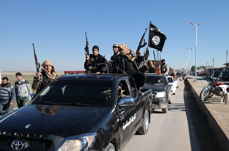 Islamic State militants pass by a convoy. (Militant website via AP)
