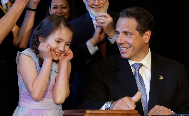 New York Governor Andrew Cuomo, right, gets some help from Amanda Houser, 10, while signing a ceremonial bill to establish a medical marijuana program in New York, Monday, July 7, 2014. New York has become the 23rd state in the U.S. to authorize medical marijuana,  though the state's program is one of the nation's most restrictive.  Cuomo signed the measure into law on Saturday and held the formal signing ceremony on Monday to highlight the new law.  When the program gets up and running in about 18 months, patients with diseases including AIDS, cancer and epilepsy will be able to obtain non-smokeable versions of the drug. Instead, the drug must be ingested or administered through a vaporizer or oil base. Houser, who has Dravet syndrome, may benefit from medical marijuana.(AP Photo/Seth Wenig)