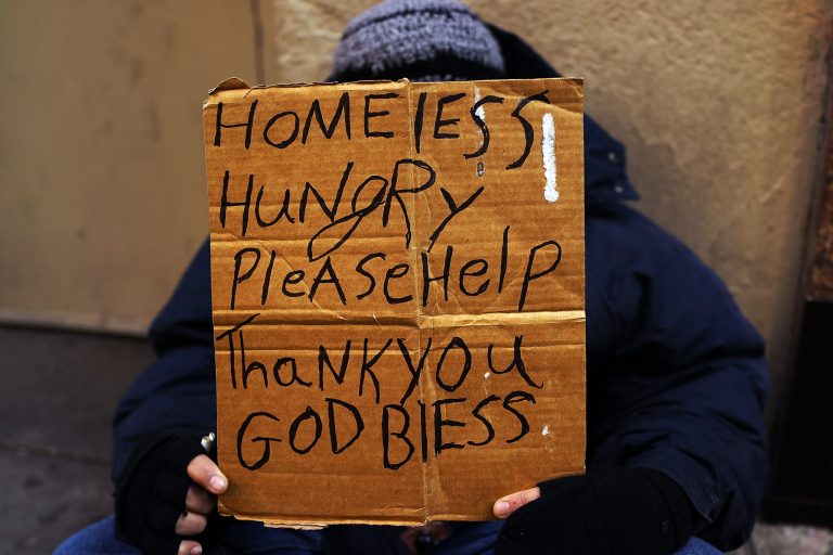 A person in economic difficulty holds a homemade sign asking for money. (Spencer Platt/Getty Images)