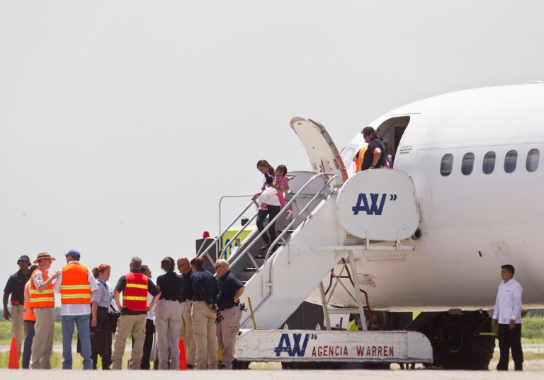 Immigration and Custom officials standby as a woman and child, who were deported from the United States, deplane at the San Pedro Sula airport, in Honduras, Friday, July 18, 2014. (AP Photo/Esteban Felix)