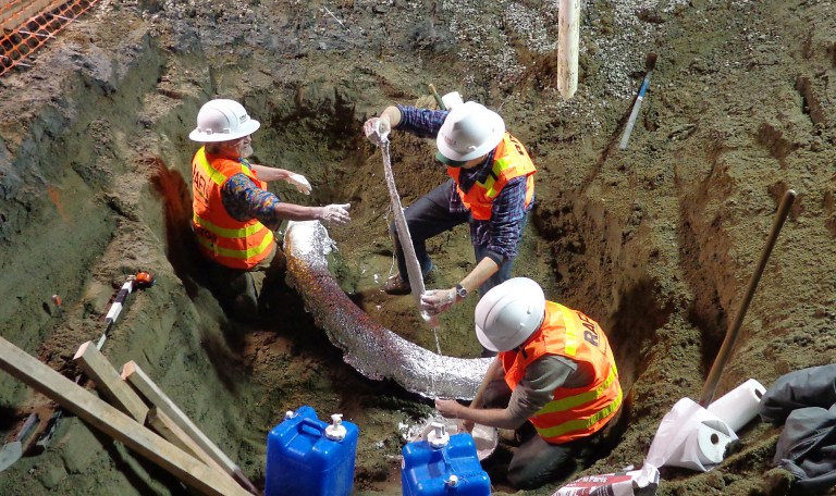 In this photo provided by the Rafn Company, Burke Museum paleontologists Bruce Crowley, left, Christian Sidor and Dave DeMar apply layers of plaster to the exposed side of a mammoth tusk early Friday morning, Feb. 14, 2014. The mammoth tusk was discovered days earlier during excavation at an apartment construction site just north of downtown. Measured at eight and one-half feet, the tusk appears to be one of the largest and most intact specimens ever found in the area. The plaster protects the tusk from bending and cracking throughout the drying process, which may take up to 12 months. (AP Photo/Rafn Company, Craig Leckness)