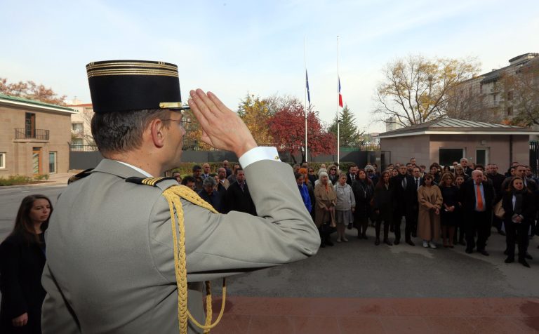 A French army officer salutes as French embassy personnel and members of French community sing La Marseillaise, French national anthem, after a minute of silence, with French and European Union flags lowered at half staff in Ankara, Turkey, Monday. (AP Photo/Burhan Ozbilici)