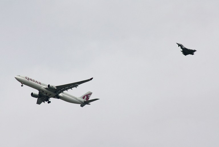 A military fighter jet escorts a passenger jet as it comes in to land at Manchester airport, Manchester, England, Tuesday, Aug. 5, 2014. Police say they have arrested a man on suspicion of making a hoax bomb threat after Qatar Airways Flight 23 landed with a military fighter escort at Britain's Manchester Airport. (AP Photo/Matthew Cossar)