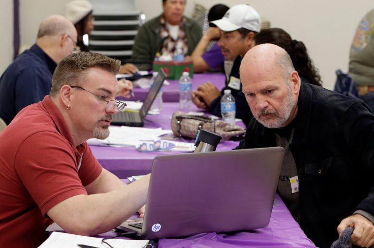 Keith Saunders, left, a certified Cover California insurance agent, explains a health insurance plan to Mark Tammes at a registration site hosted by Service Employees International Union-United Healthcare Workers, Monday, March 31, 2014, in Sacramento, Calif. Tammes, 57, a violinist with the Sacramento Philharmonic, was among the dozens who attended the event to sign up for health coverage ahead of Monday's midnight enrollment deadline. (AP Photo/Rich Pedroncelli)