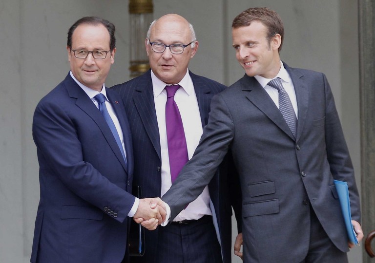 France's President Francois Holland, left, shakes hands with France's new Economy Minister Emmanuel Macron, right, as French finance minister Michel Sapin, centre, looks on,  as they leave their weekly cabinet meeting, in Paris, Wednesday, Aug. 27, 2014. France's prime minister reshuffled his Cabinet on Tuesday to silence ministers who had openly criticized Socialist President Francois Hollande's economic policies as he tries to pull the nation out of stagnation and steer it toward growth. (AP Photo/Christophe Ena)