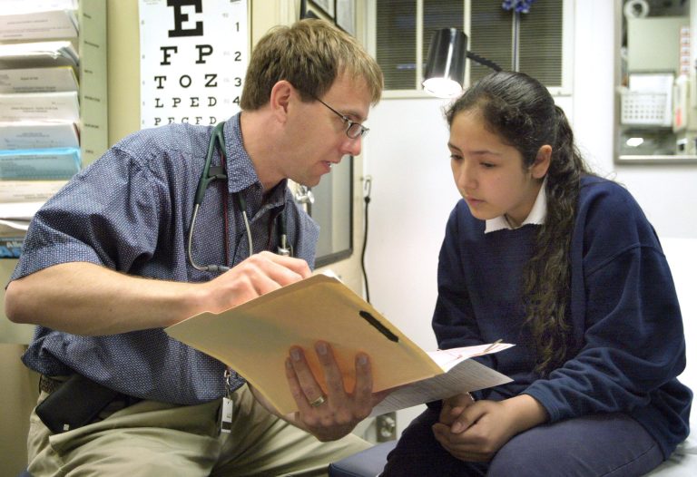 Dr. Michael Paul, with the Pediatric Mobile Health Unit of Loyola University Medical Center, talks with fourth-grader Bennita Correa after her physical exam for incoming fifth-graders outside David Burnham Elementary School May 11, 2004 in Cicero, Ill. (Photo by Tim Boyle/Getty Images)