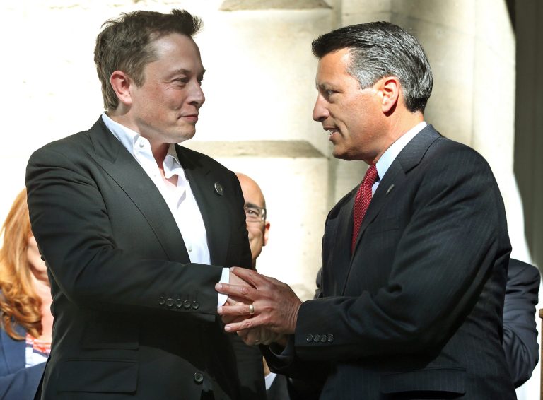 Tesla Motors CEO Elon Musk, left, and Nevada Gov. Brian Sandoval shake hands following a news conference where Nevada was announced as the new site for a car battery gigafactory, at the Capitol in Carson City, Nev. Nevada will have nearly 35,000 more residents in the year 2032 than it would have if the state hadn't landed the Tesla Motors battery factory and another major business, according to new projections released Oct. 8. (AP Photo/Cathleen Allison, File)