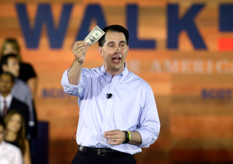 Wisconsin Gov. Scott Walker hold a dllar bill as speaks to supporters as he announces he is running for the 2016 Republican presidential nomination at the Waukesha County Expo Center, July 13, 2015, in Waukesha, Wis. (AP Photo/Morry Gash)