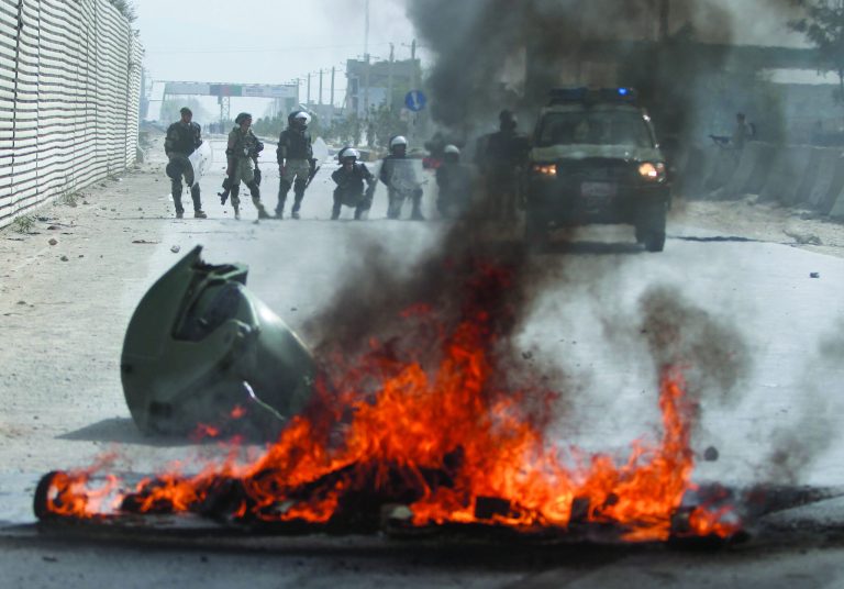 Afghan police stand by burning tires during a protest, in Kabul, Afghanistan, Monday, Sept. 17, 2012. Hundreds of Afghans burned cars and threw rocks at a U.S. military base as a demonstration against an anti-Islam film that ridicules the Prophet Muhammad turned violent in the Afghan capital early Monday. (AP Photo/Ahmad Jamshid)