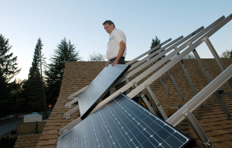 Phil Tussing installs photovoltaic solar panels on a residence November 17, 2005 in Portland, Ore. Residential solar panels for both electricity production and water heating represent a growing trend for home owners in Oregon seeking energy efficiency. (Photo by Melanie Conner/Getty Images)