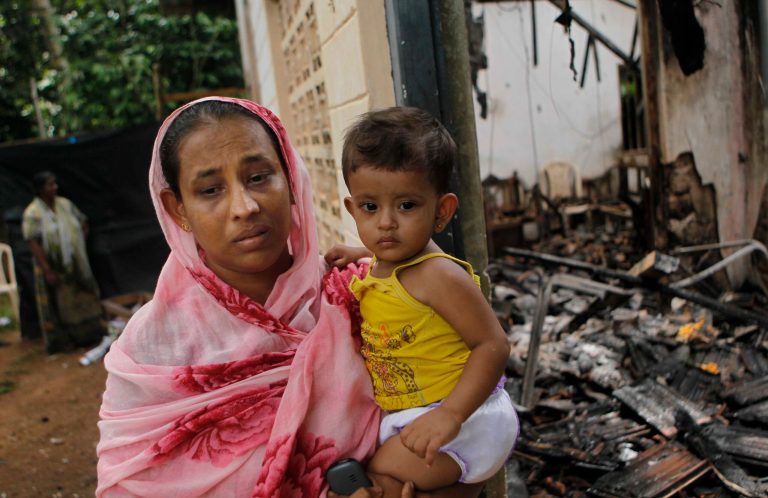 A Sri Lankan Muslim woman carries her daughter while standing outside her burnt house in Adhikarigoda , a village near Aluthgama town, 50 kilometers (31.25 miles) south of Colombo, Sri Lanka, Monday, June 16, 2014. At least three Muslims were killed after a right-wing Buddhist group with alleged state backing clashed with Muslims in southwestern Sri Lanka, a government minister said Monday. Dozens of shops were burned, homes looted and some mosques attacked in the violence Sunday night in the town of Aluthgama, local residents said. (AP Photo/Eranga Jayawardena)