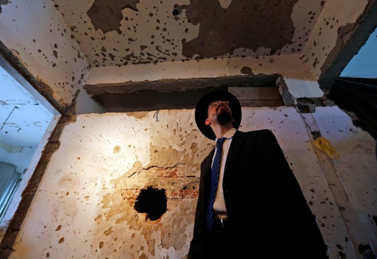 Rabbi Moshe Gourarie from New Jersey looks at a wall riddled with bullet marks from the 2008 terror attack at the Chabad Center, during the reopening of the Jewish center in Mumbai, India, Tuesday, Aug. 26, 2014. Rabbis from across Asia on Tuesday celebrated the reopening of the center targeted by rampaging Pakistani gunmen who stormed through Mumbai on a 60-hour killing spree that left 166 people dead. Rabbi Israel Kozlovsky, who now runs the Mumbai center, said the rebuilt six-story Nariman House would house a $2.5 million Jewish Museum as well as Mumbai's first memorial to those killed in the attacks, which also targeted a train station, a popular tourist cafe and the luxury Taj Mahal hotel. (AP Photo/Rajanish Kakade)