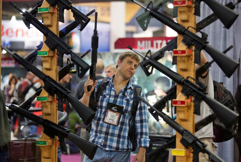 This Jan. 17, 2013 file photo shows Michael Kiefer of DeFuniak Springs, Fla., checking out a display of rifles at the Rock River Arms booth during the 35th annual SHOT Show in Las Vegas. (AP Photo/Julie Jacobson)
