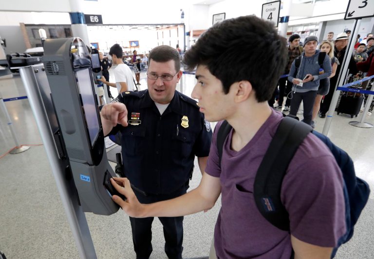U.S. Customs and Border Protection supervisor Erik Gordon, left, helps passenger Ronan Pabhye navigate one of the new facial recognition kiosks at a United Airlines gate before boarding a flight to Tokyo on July 12, 2017, at George Bush Intercontinental Airport, in Houston. The Trump administration intends to require that American citizens boarding international flights submit to face scans, something Congress has not explicitly approved and privacy advocates consider an ill-advised step toward a surveillance state. (AP Photo/David J. Phillip)