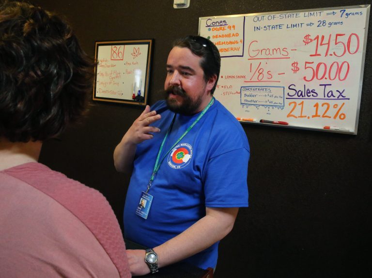 In this Feb. 14 file photo, pot store employee Sam Walsh informs a first time customer about different strains of marijuana, a white board listing prices and sales tax, inside the retail shop at 3D Cannabis Center, in Denver. Colorado Gov. John Hickenlooper announced a plan to start spending nearly $100 million in marijuana tax money, the first signal of how much Colorado is reaping from recreational pot sales and what it plans to spend the money on. (AP Photo/Brennan Linsley)