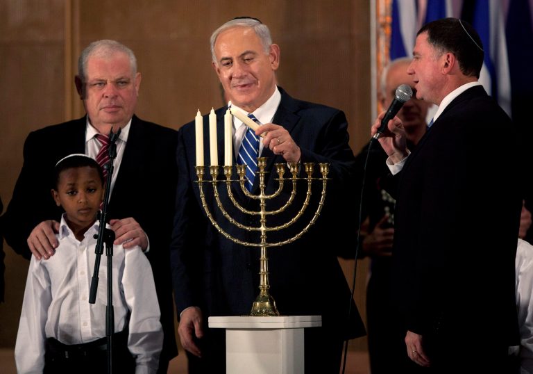   Israeli Prime Minister Benjamin Netanyahu lights candles on the Jewish holiday of Hanukkah during an event with foreign press in Jerusalem, Monday, Dec. 10, 2012. Netanyahu is accusing the international community of double standards, saying it condemns Israeli settlements in the West Bank but not Palestinians' refusal to renew peace talks or militant group Hamas' call for the end of the Jewish state. (AP Photo/Sebastian Scheiner)  