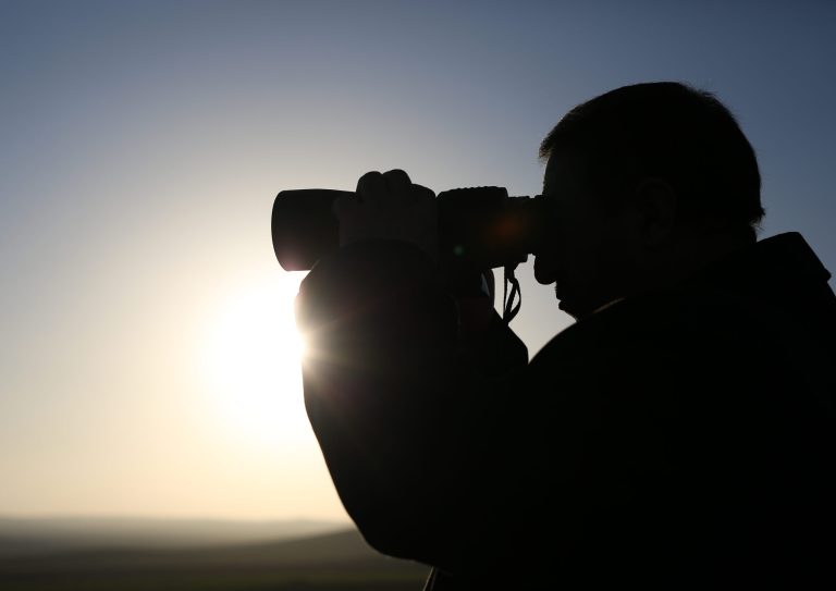 A man uses binoculars to see the devastated Syrian city of Ain al-Arab, also known as Kobani, from border town of Suruc, Turkey, Sunday, Feb. 1, 2015. The Islamic State group has acknowledged for the first time that its fighters have been defeated in the Syrian town of Kobani and vowed to attack the town again. In a video released by the pro-IS Aamaq News Agency late Friday, two fighters said the airstrikes by the U.S.-led coalition were the main reason why IS fighters were forced to withdraw from Kobani.(AP Photo/Emrah Gurel)