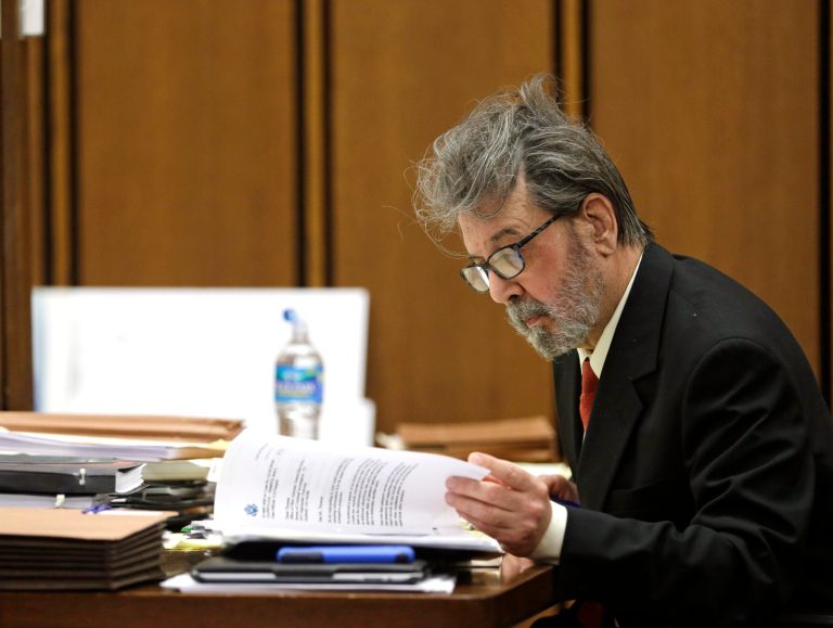 Defendant Bobby Thompson, who authorities say is a Harvard-trained attorney and former military intelligence officer named John Donald Cody, looks over papers during his trial Tuesday, Nov. 5, 2013, in Cleveland. (AP/Tony Dejak)
