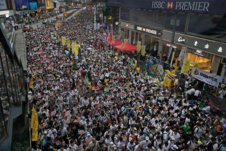Tens of thousands of people fill in a street during a march at an annual protest in downtown Hong Kong Tuesday, July 1, 2014. Hong Kong residents marched through the streets of the former British colony to push for greater democracy in a rally fueled by anger over Beijing's recent warning that it holds the ultimate authority over the southern Chinese financial center. The protest comes days after nearly 800,000 residents voted in a mock referendum aimed at bolstering support for full democracy. (AP Photo/Vincent Yu)
