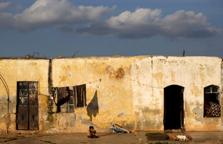   A Syrian child looks at a cat while sitting in front in front of his home, in Maaret Misreen, near Idlib, Syria, Friday, Dec. 14, 2012. (AP Photo/Muhammed Muheisen)  