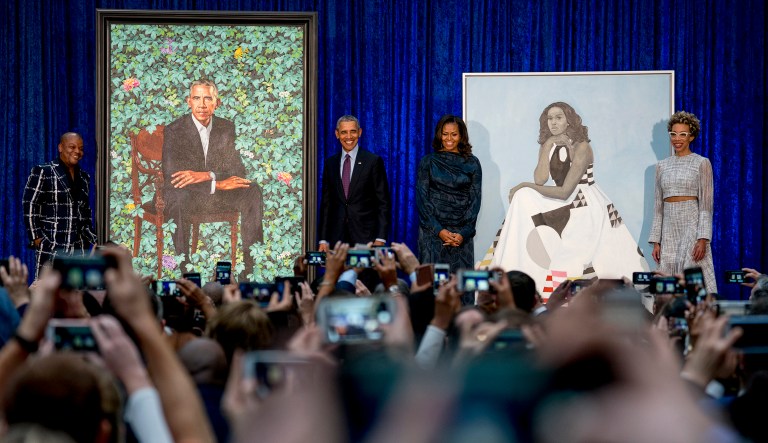Former President Barack Obama and first lady Michelle Obama stand next to their portraits during the unveiling ceremony. Artist Kehinde Wiley painted the president's portrait, and Amy Sherald painted Michelle Obama's portrait. (AP Photo/Andrew Harnik)