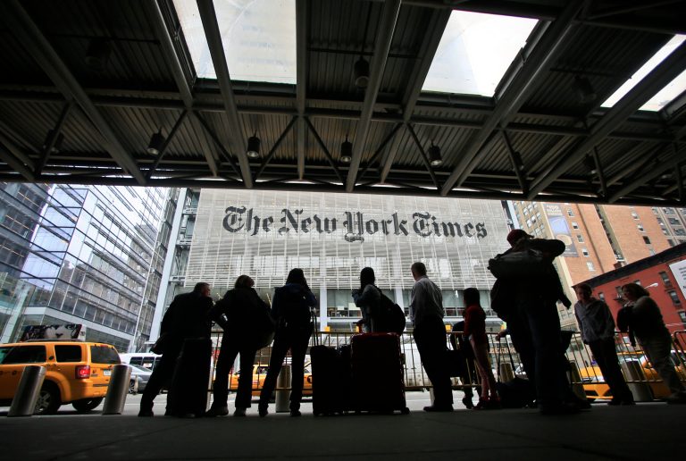 Pedestrians wait for cabs across the street from The New York Times in New York. (AP)