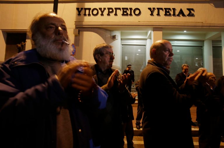 Protesters applaud a speaker during a protest outside Health Ministry in Athens on Tuesday, Feb. 18, 2014. Several thousand supporters of a Communist labor union marched in central Athens Tuesday to protest an overhaul of the country's national health system that has led to months of strikes. The government has ordered a shake up of the main health care fund EOPYY, stopping the agency's direct involvement on care provision. The changes were introduced as part of the country's bailout commitments. (AP Photo/Thanassis Stavrakis)