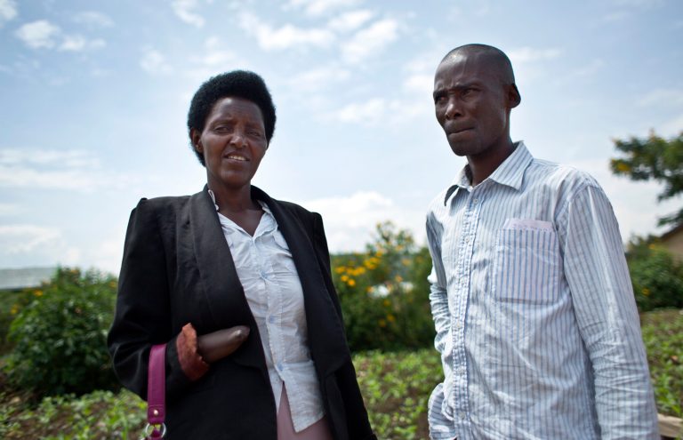 In this photo taken Wednesday, March 26, 2014, Emmanuel Ndayisaba, right, and Alice Mukarurinda, pose for a photograph outside Alice's house in Nyamata, Rwanda. She lost her baby daughter and her right hand to a manic killing spree. He wielded the machete that took both. Yet today, despite coming from opposite sides of an unspeakable shared past, Alice Mukarurinda and Emmanuel Ndayisaba are friends. She is the treasurer and he the vice president of a group that builds simple brick houses for genocide survivors. They live near each other and shop at the same market. Their story of ethnic violence, extreme guilt and, to some degree, reconciliation is the story of Rwanda today, 20 years after its Hutu majority killed more than 1 million Tutsis and moderate Hutus. The Rwandan government is still accused by human rights groups of holding an iron grip on power, stifling dissent and killing political opponents. But even critics give President Paul Kagame credit for leading the country toward a peace that seemed all but impossible two decades ago. (AP Photo/Ben Curtis)