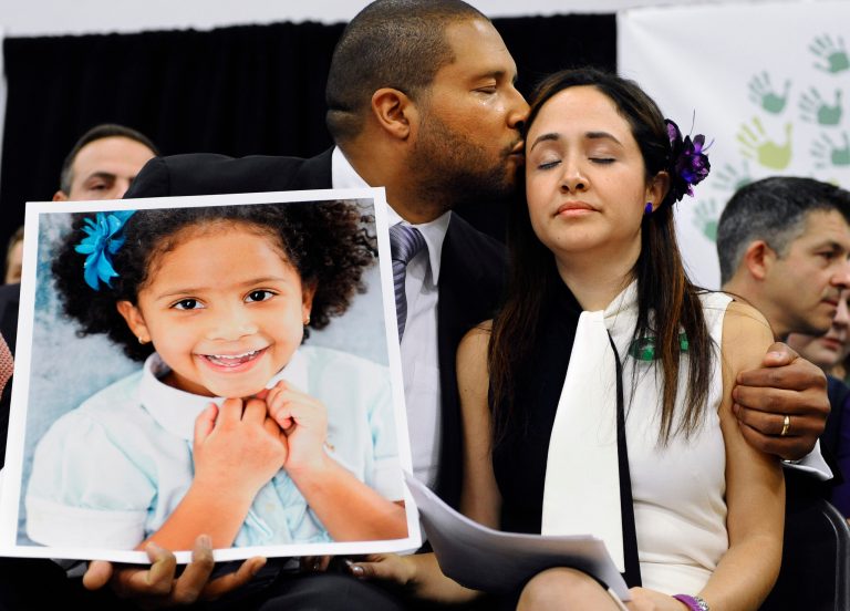 Jimmy Greene, left, kisses his wife Nelba Marquez-Greene while holding a portrait of their daughter, Sandy Hook Elementary School shooting victim Ana Marquez-Greene, in Newtown, Conn. Ana Marquez-Greene was one of 26 people killed when Adam Lanza opened fire inside the school on Dec. 14, 2012, in Newtown, Conn.  (AP Photo/Jessica Hill, File)