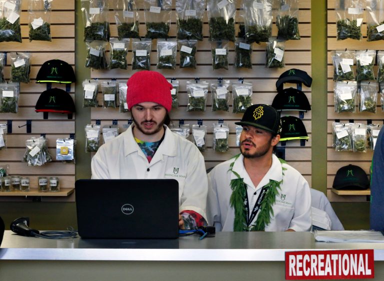 Employees David Marlow, right, and Chris Broussard work behind the sales counter inside Medicine Man marijuana retail store, which opened as a legal recreational retail outlet in Denver on Jan. 1. (AP Photo/Brennan Linsley)