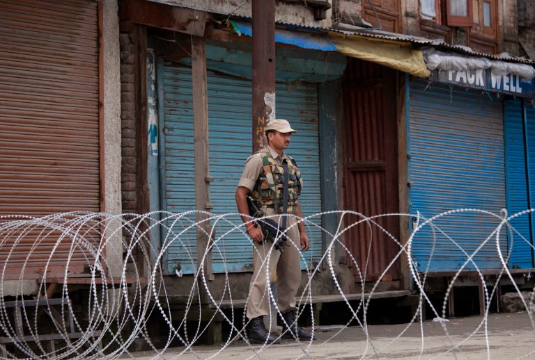 An Indian paramilitary soldier stands guard near a barbed wire set up as road blockade during restrictions in Srinagar, India, Friday, July 4, 2014. Shops, businesses and schools are shut in Indian-controlled Kashmir after separatist groups opposed to Indian rule announced a strike to protest a visit by the country's Prime Minister Narendra Modi. Modi is on his first official visit to the disputed Himalayan region and is expected to inaugurate a railway line and a power station, and also review security and development. (AP Photo/Dar Yasin)