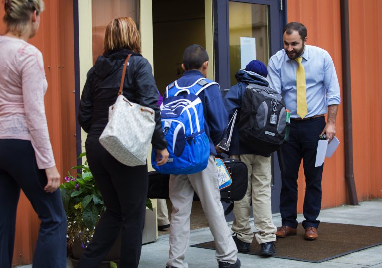 Parents, guardians and students are greeted by Adel Sefrioui, founder and executive director of Excel Public Charter School in Kent, Wash., as they enter school Tuesday, Sept. 8, 2015. (Ellen M. Banner/The Seattle Times via AP)