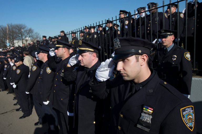 Police officers salute as the hearse of New York city police officer Rafael Ramos drives along his funeral procession route in the Glendale section of Queens, Saturday, Dec. 27, 2014, in New York. (AP Photo/John Minchillo)