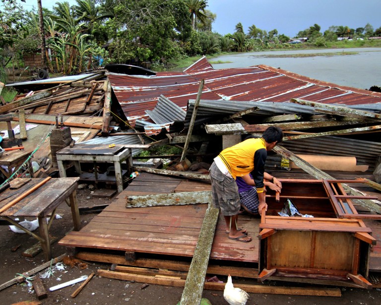   Residents prepare to assess their house which was damaged by Typhoon Bopha in Butuan city in southeastern Philippines Tuesday Dec. 4, 2012. A Philippine governor says at least 33 villagers and soldiers have drowned when torrents of water dumped by the powerful typhoon rushed down a mountain, engulfing the victims and bringing the death toll from the storm to about 40. (AP Photo/Erwin Mascarinas)  