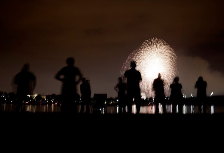 People watch from Arlington along the shore of the Potomac River as fireworks are shot over the National Mall in Washington on July 4, 2011.  (Photo by Brendan Smialowski/Getty Images)