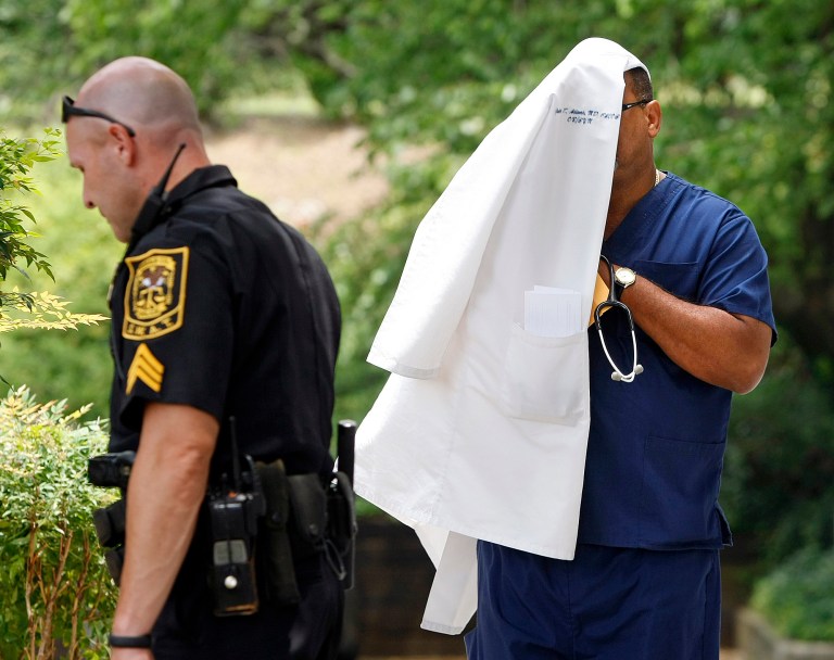 FILE- In this June 14, 2012 file photo, a doctor covers his head with his medical coat as he leaves the Southern Health Management building during a 