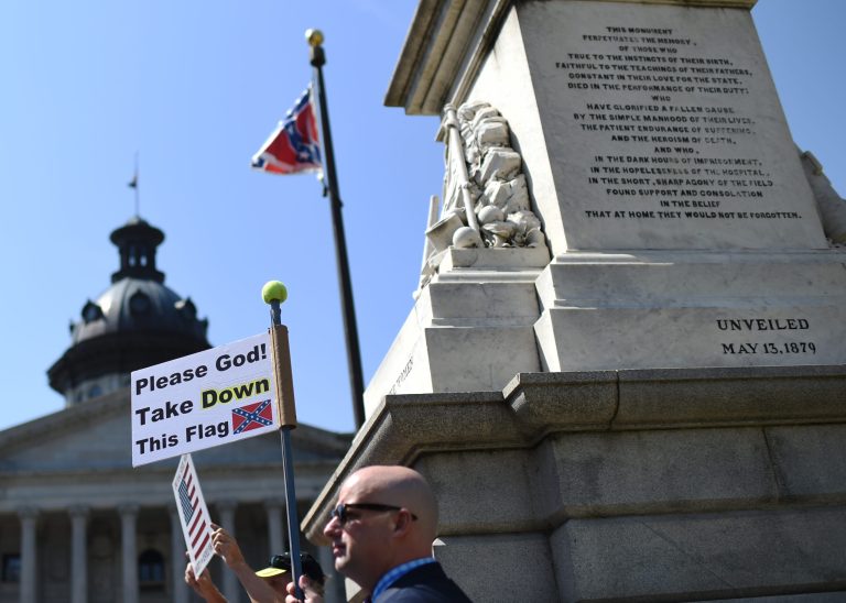 An individual holds a sign during a rally to take down the Confederate flag at the South Carolina Statehouse, Tuesday, June 23, 2015, in Columbia, S.C. The shooting deaths of nine people at a black church in Charleston, S.C, have reignited calls for the Confederate flag flying on the grounds of the Statehouse in Columbia to come down. (AP Photo/Rainier Ehrhardt)