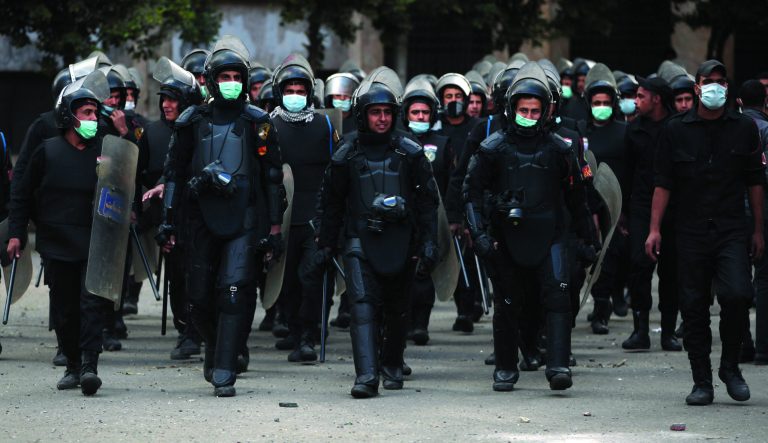 Egyptian riot police march during clashes with protesters, not seen, near Tahrir Square in Cairo, Egypt, Wednesday, Jan. 30, 2013. Egypt's liberal opposition leader called for a broad national dialogue with the Islamist government, all political factions and the powerful military on Wednesday, aimed at stopping the country's eruption of political violence that has left scores dead in the past week. (AP Photo/Khalil Hamra)