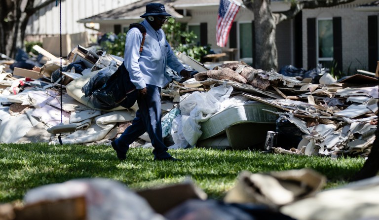 Postal worker Lonzell Rector makes his rounds among flood damaged debris from homes that lines the street in the aftermath of Hurricane Harvey on Thursday, Sept. 7, 2017, in Houston. (AP Photo/Matt Rourke)