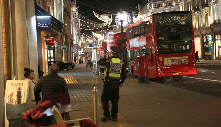 People are ushered by a police officer down a street in the west end of London after Oxford Circus station was evacuated Friday Nov. 24, 2017. (Isabel Infantes/PA via AP)