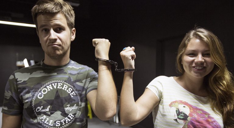 In this Sept. 22, 2014 photo, Konstantin Elizarov and Lucy Omelchenko are handcuffed together as they prepare to play a game at Escape the Quest in Miami Beach, Fla. Escape the Quest offers two games; Apartment 101 and Prison Escape, where groups of two to four have an hour to solve a puzzle and win their freedom. (AP Photo/J Pat Carter)