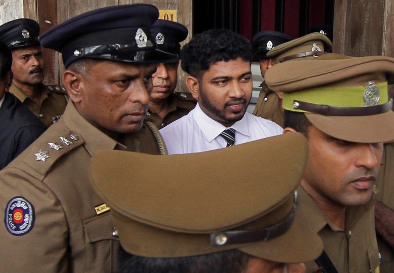 Police officials escort Sampath Vidanapathirana, a ruling party politician, convicted in a murder and rape case at the High Court complex in Colombo, Sri Lanka, Friday, July 18, 2014. A Sri Lankan court on Friday sentenced Vidanapathirana to 20 years in prison for killing a British tourist Khuram Sheikh and raping his Russian girlfriend more than two years ago. (AP Photo/S. Gayashan)