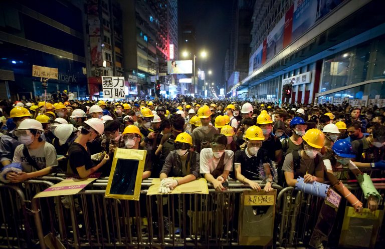 Protesters stand guard behind a barricade at the occupied area in the Mong Kok district of Hong Kong, early Monday, Oct. 20, 2014. Three weeks ago, students at a rally stormed a fenced-off courtyard outside Hong Kong's government headquarters, triggering unprecedented mass protests for greater democracy in the semiautonomous Chinese city. (AP Photo/Kin Cheung)