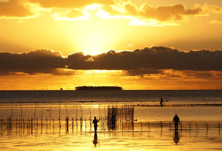 In this Wednesday, June 4, 2014 photo, fisher folk work on in shallow waters, near Nuku'alofa, Tonga. New Zealand tourists attracted by the country's beauty have been staying away due to a dispute over the safety of a plane built in China. The dispute represents a small skirmish in a broader battle for global influence. (AP Photo/Nick Perry)