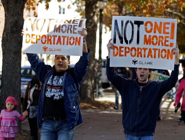 Two men march with a sign during a protest in front of a building that houses federal immigration offices Tuesday, in Atlanta. Several people were arrested. (AP Photo/John Bazemore)