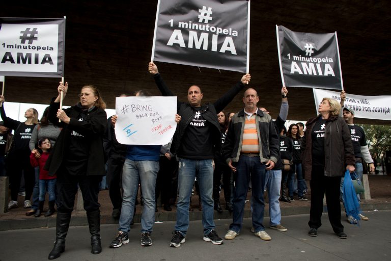 People hold up signs after a minute of silence as the Argentina-Iran World Cup game kicks off in Sao Paulo, Brazil, Saturday, June 21, 2014. The protest was held to mark 20 years since the unsolved bombing attack against a Buenos Aires Jewish center that left 85 dead. Prosecutors blame Iran for the attack. The hashtag reads in Portuguese 