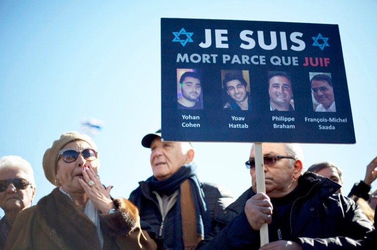 French Israelis, one holding a poster with portraits of four Jewish victims of the terrorist attack last week on a kosher grocery store in Paris, attend their funeral, at Givat Shaul cemetery in Jerusalem, Israel, Tuesday. (AP Photo/Ariel Schalit)